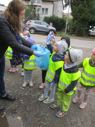 Akcja sprzątamy dla Polski w grupie 4 Wiewiórki – dzieci wrzucają śmieci do worka