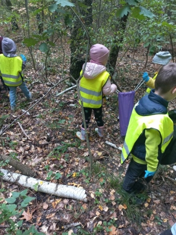 Dzieci chodzą po lesie i szukają odpadów.