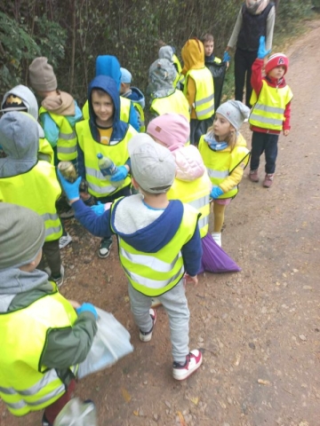 Dzieci chodzą po lesie i zbierają odpady.