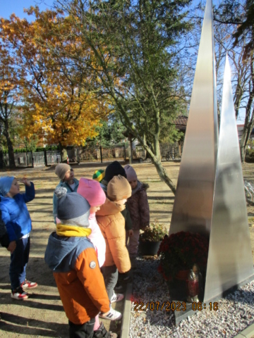 Dzieci stoją przed pomnikiem załogi samolotu B17, na terenie Szkoły Podstawowej w Dziekanowie Leśnym.