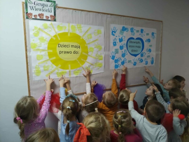 Dzień Praw Dziecka w grupie Wiewióreczek – dzieci z grupy pokazują wykonane przez siebie plakaty Prawa dzieci i Obowiązki dzieci, powieszone na gazetce w korytarz (3)