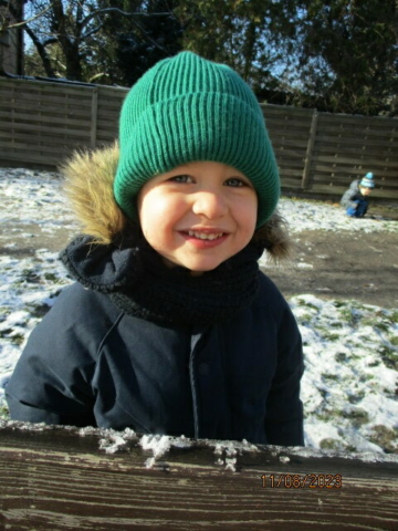 Chłopiec z grupy II bawi się na śniegu