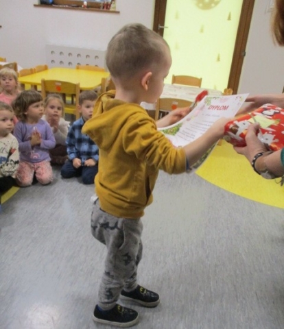 Chłopiec z gr 1 odbiera dyplom za udział w konkursie Bożonarodzeniowym.